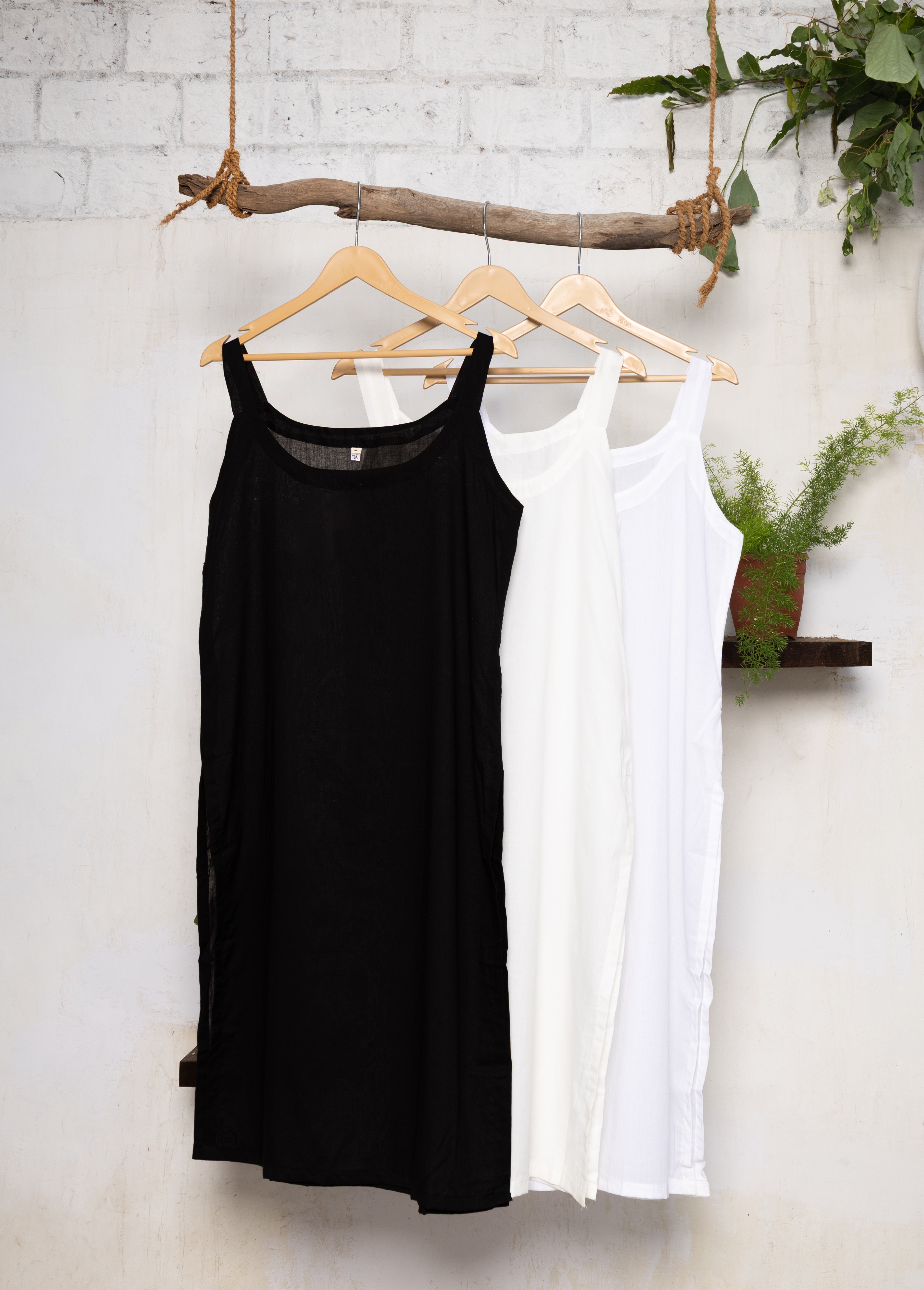 Set of three 100% cotton slips in black, white, and off-white with round neckline and side slits, perfect for layering.
